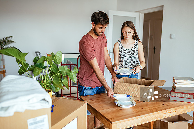 情侣搬进新公寓，从箱子里取出陶器并擦拭灰尘图片素材