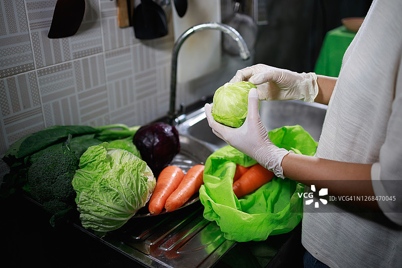 戴手套的女子正在从蔬菜中分离污染物和异物图片素材