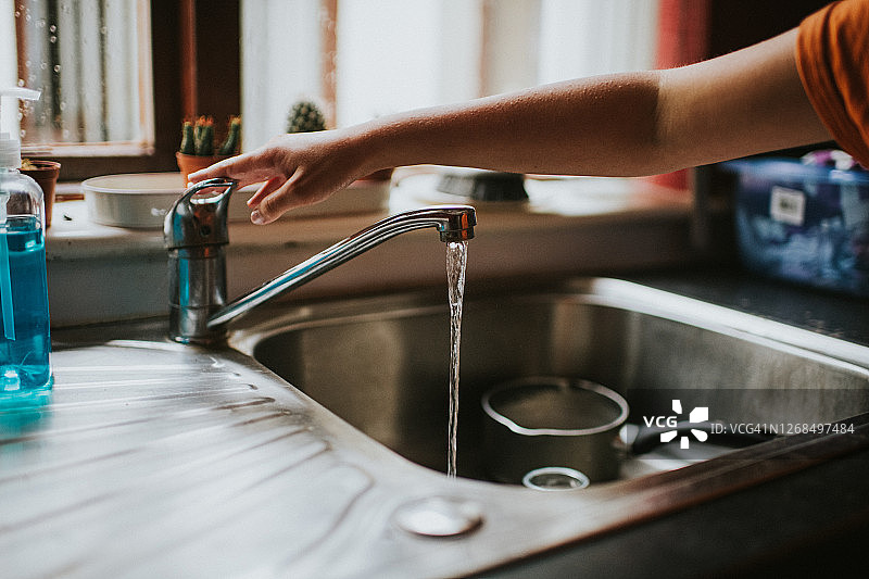 在厨房里关掉自来水龙头的手图片素材
