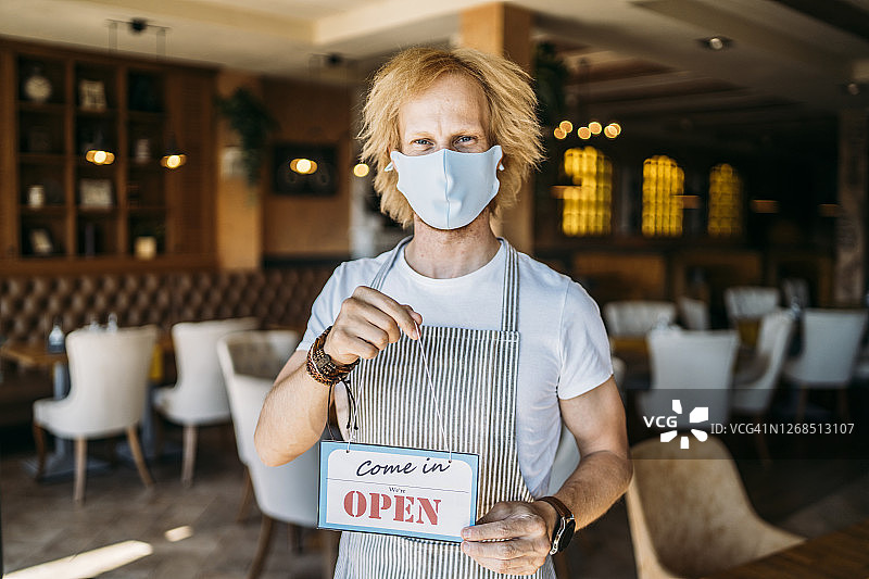 餐厅老板拿着营业中的牌子图片素材