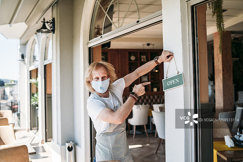 服务员手持“营业中”标牌图片素材