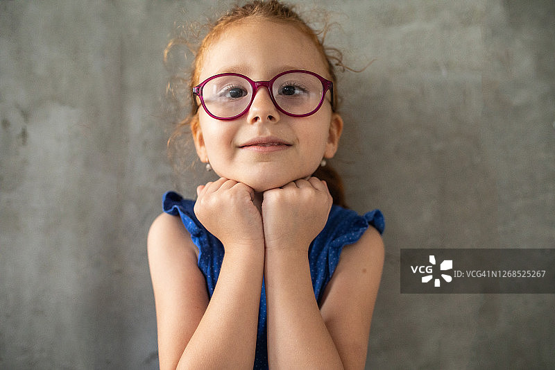 在家中灰色墙壁前的红发斗鸡眼女孩图片素材