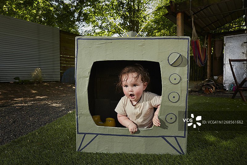 宝宝从纸板电视里爬出来图片素材