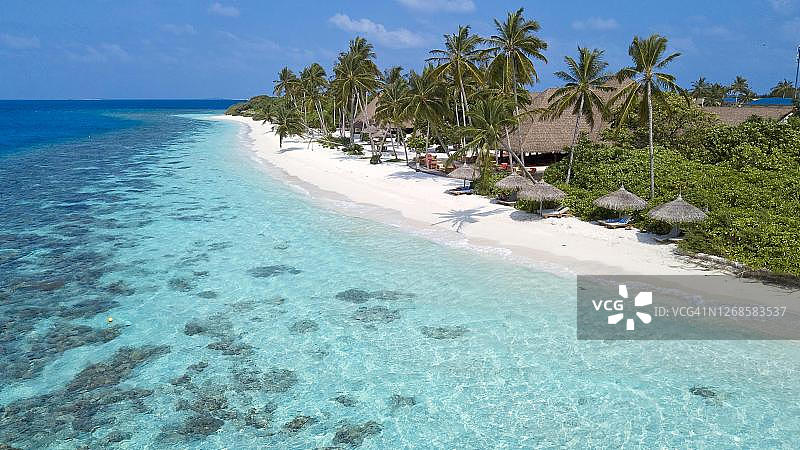 鸟瞰：马尔代夫拉环礁菲莱杜岛，泻湖和海滩上覆盖着棕榈树的遮阳伞和椰子树图片素材