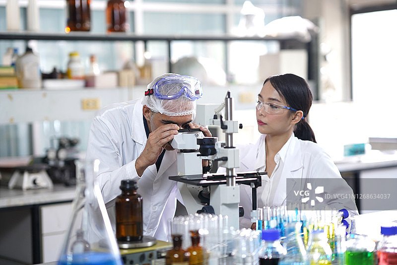 研究人员在科学实验室里用显微镜观察细胞图片素材