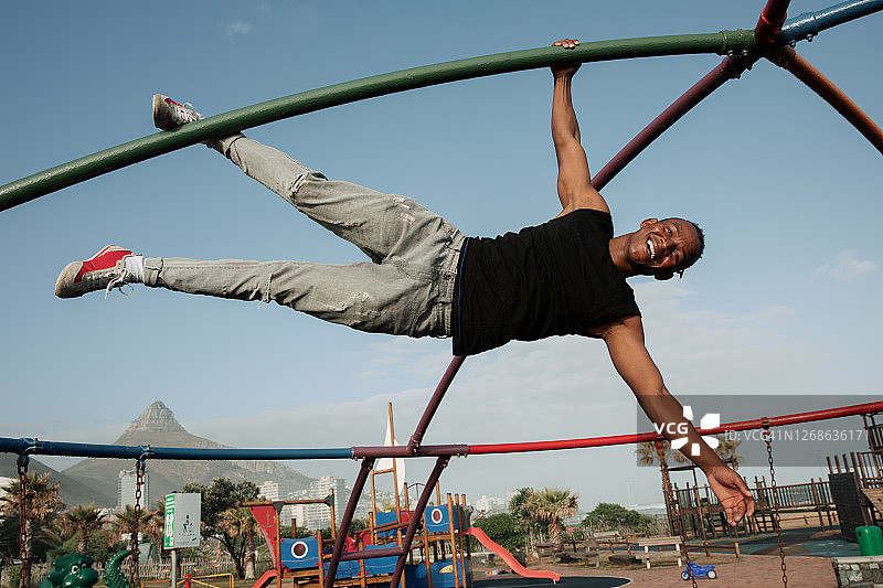 手臂和腿挂在攀爬结构上的英俊强壮年轻人图片素材