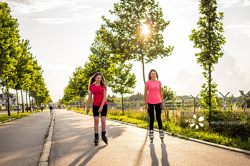 阳光明媚的日子里滑旱冰的两个朋友图片素材