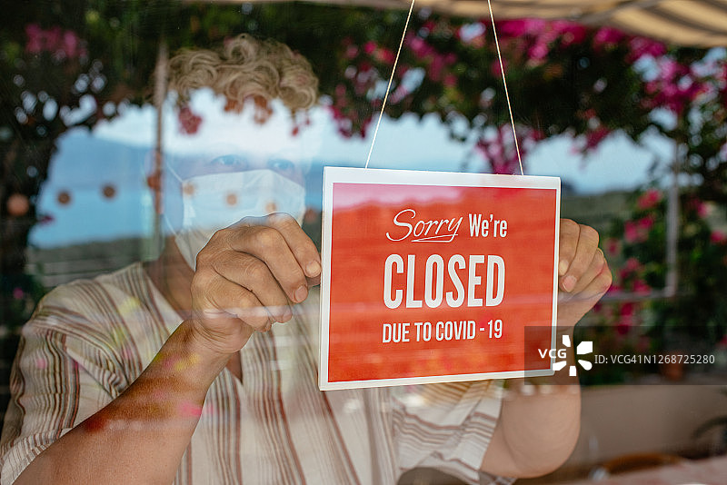 戴口罩的企业主挂出暂停营业标志图片素材