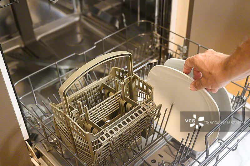 男人将餐具放入洗碗机图片素材