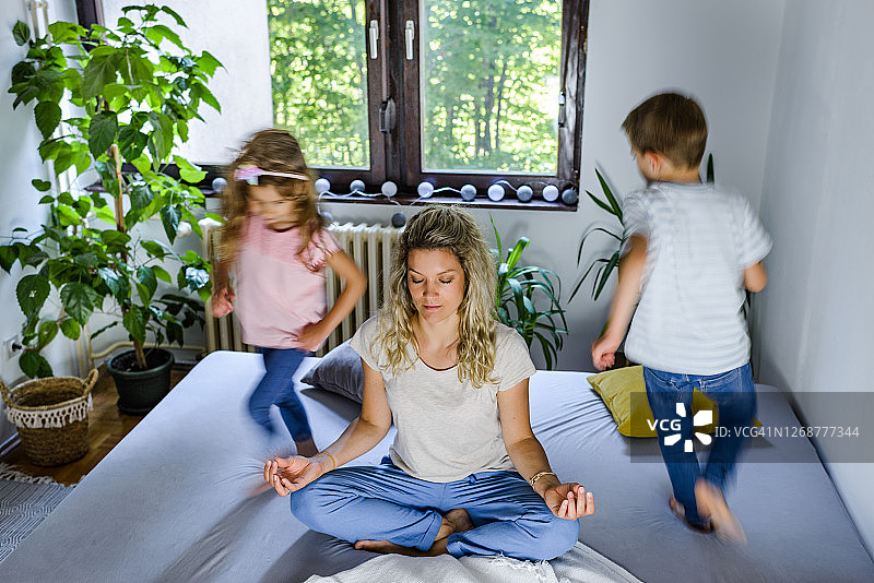 在嘈杂的孩子们奔跑时，年轻的母亲在冥想图片素材