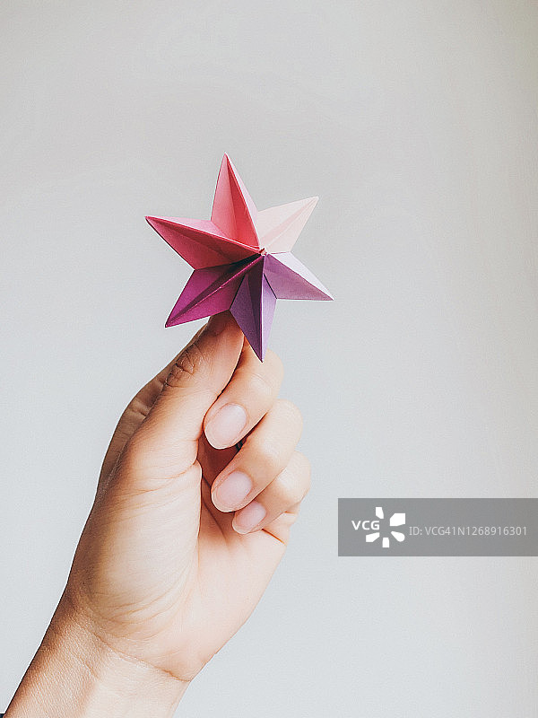 女人手拿一个多米诺骨牌星折纸图片素材