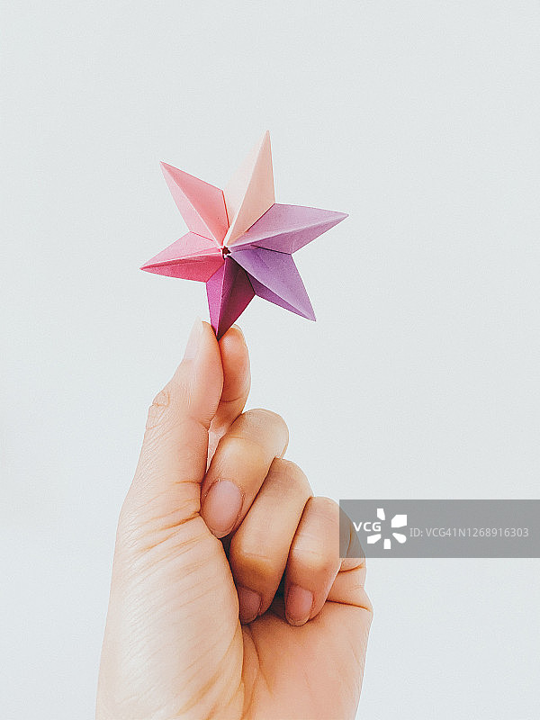 女人手拿一个多米诺骨牌星折纸图片素材