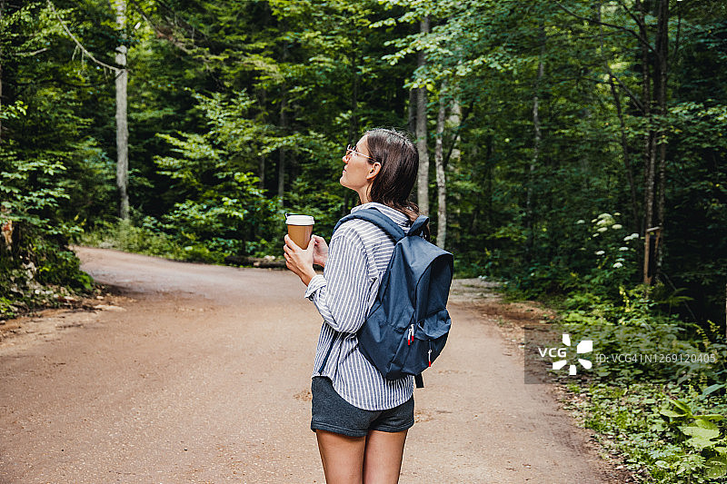 女人在树林中的道路上行走并使用智能手机图片素材