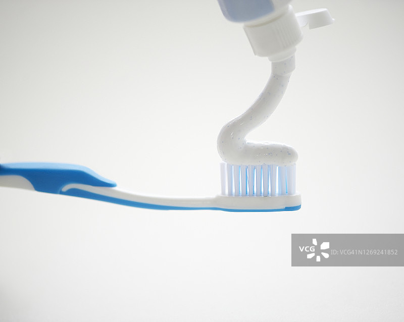 特写：将牙膏涂在蓝色牙刷上图片素材