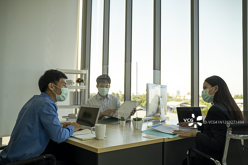 办公室里用玻璃隔断分隔工作的商务人士图片素材