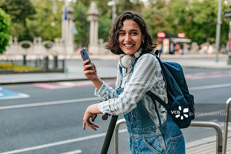 在街上使用智能手机的千禧一代女性和电动滑板车图片素材