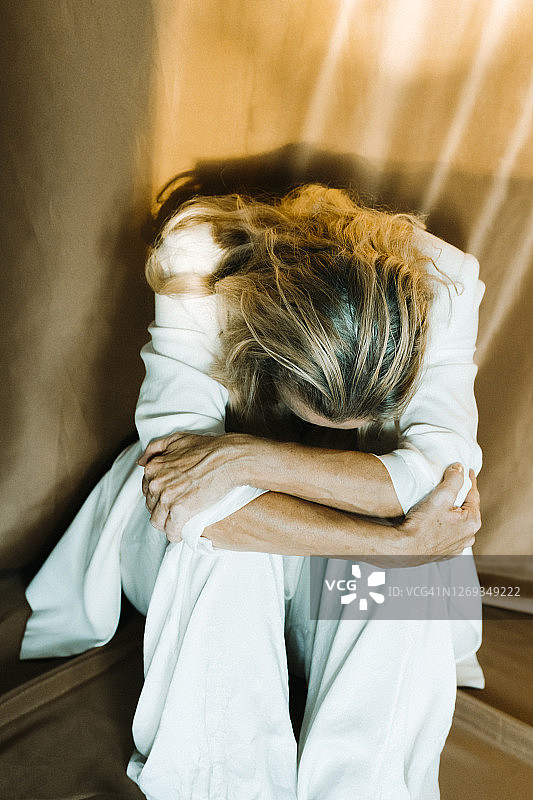 坐在窗帘旁的孤独老年妇女图片素材