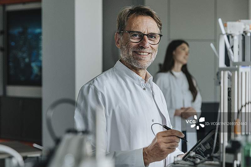 科学家在实验室发明机械，女同事在背景中图片素材