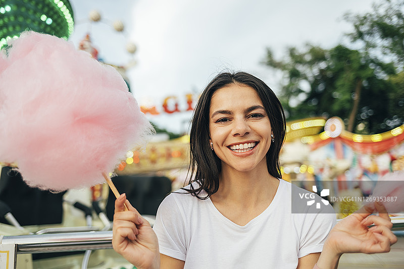在游乐园拿着棉花糖的微笑美丽女人图片素材