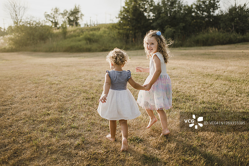 在草地上手牵手行走的女孩们图片素材