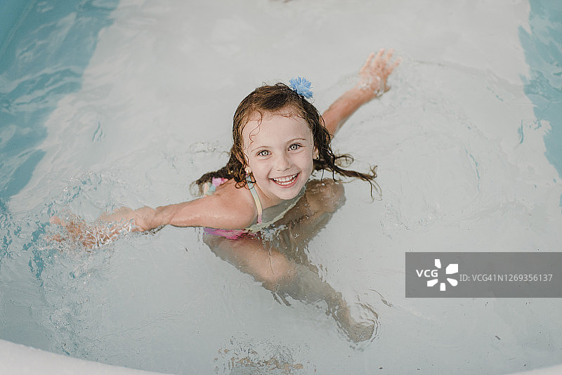 在充气游泳池里快乐的女孩肖像图片素材