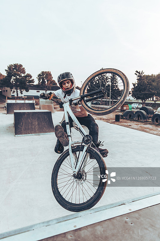 夕阳下在公园坡道上骑自行车的年轻男子图片素材