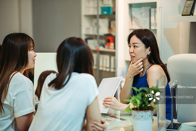 中国亚洲美丽的微笑女性在面部美容院向顾客讲解包裹图片素材