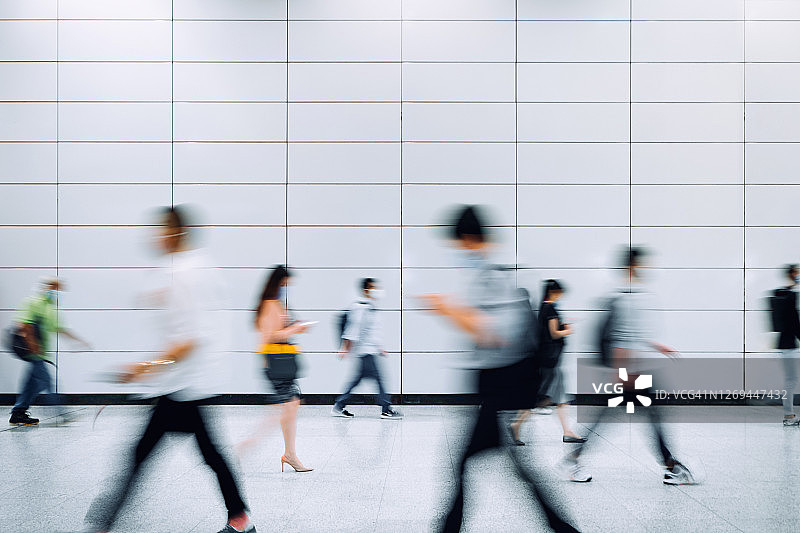 早高峰时段，地铁站台上戴口罩的通勤人群模糊掠影图片素材