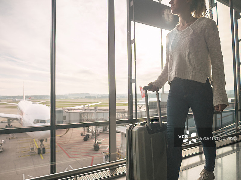拖着手提行李箱在机场行走的女人图片素材