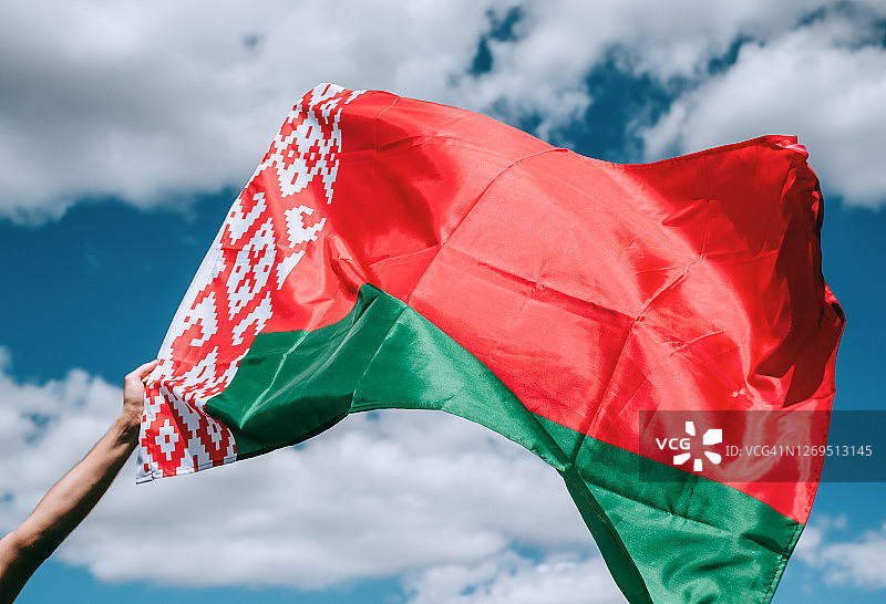蓝天背景上手持白俄罗斯国旗图片素材