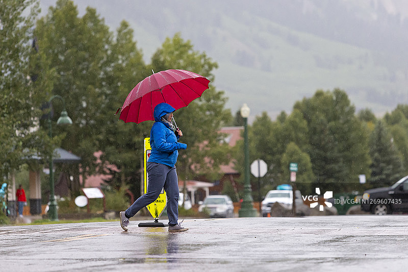 在雨中打着伞和彩虹下行走图片素材