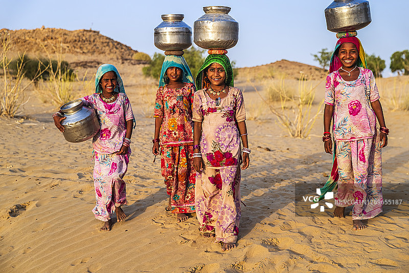 印度年轻女孩从井里取水，沙漠村庄图片素材