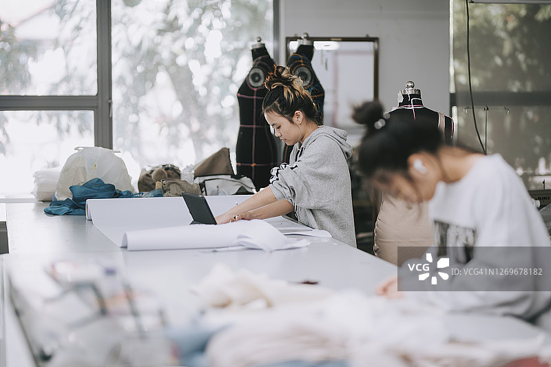 亚洲华人女时装大学生在学院工作室一起做服装项目图片素材
