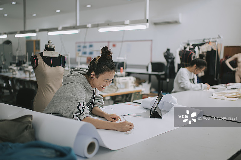 中国亚裔女大学生在工作室绘制服装裁剪图图片素材