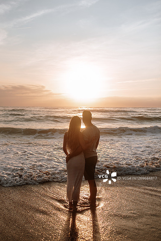 年轻情侣看着日落的背影图片素材