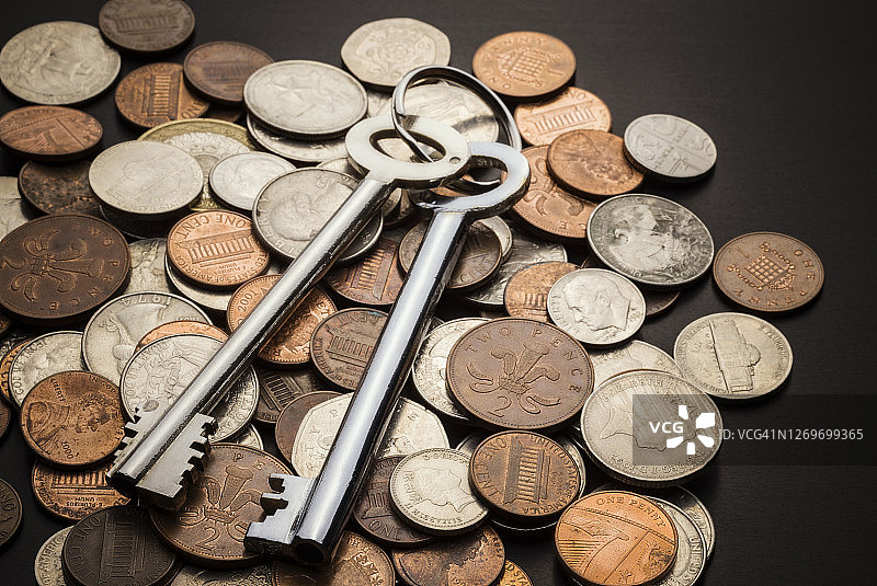 银黄铜钥匙置于硬币堆上图片素材