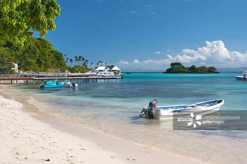 大西洋翠绿水面和白色沙滩上摇曳的船只，风景如画的木制码头图片素材