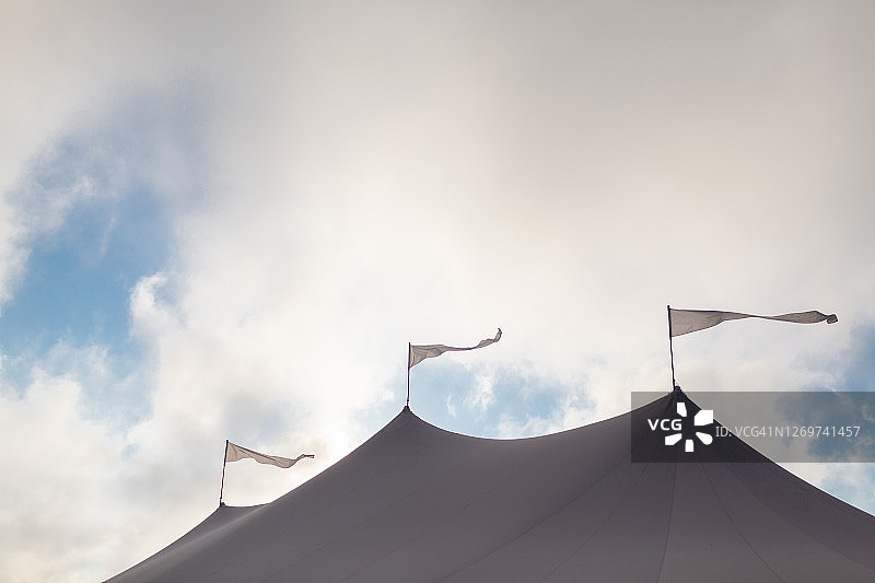 阴天里大型活动帐篷顶部的旗帜图片素材