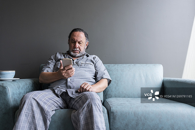 疫情隔离期间使用手机的老年男人图片素材