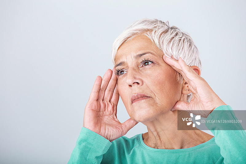 饱受压力或头痛折磨的女性。老年妇女偏头痛，感觉不舒服。一个迷人的女人的肖像，头痛，感觉疼痛图片素材