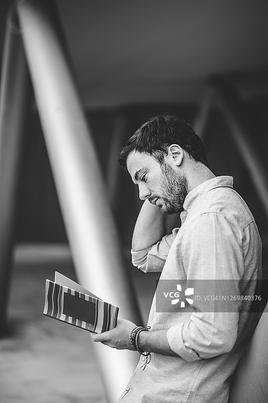 年轻男子在户外阅读书籍图片素材