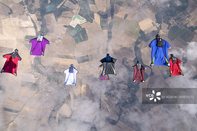 翼装飞行员编队翱翔于田园风光之上图片素材