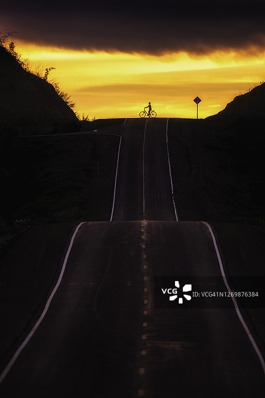 泰国南邦，夏日彩色日落时公路上的男孩剪影图片素材