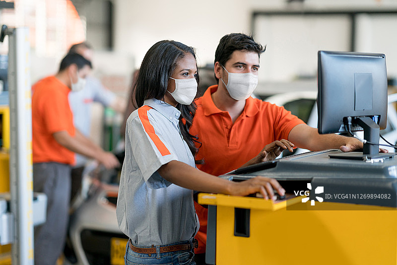 新冠疫情期间，工人在车库戴着口罩工作图片素材