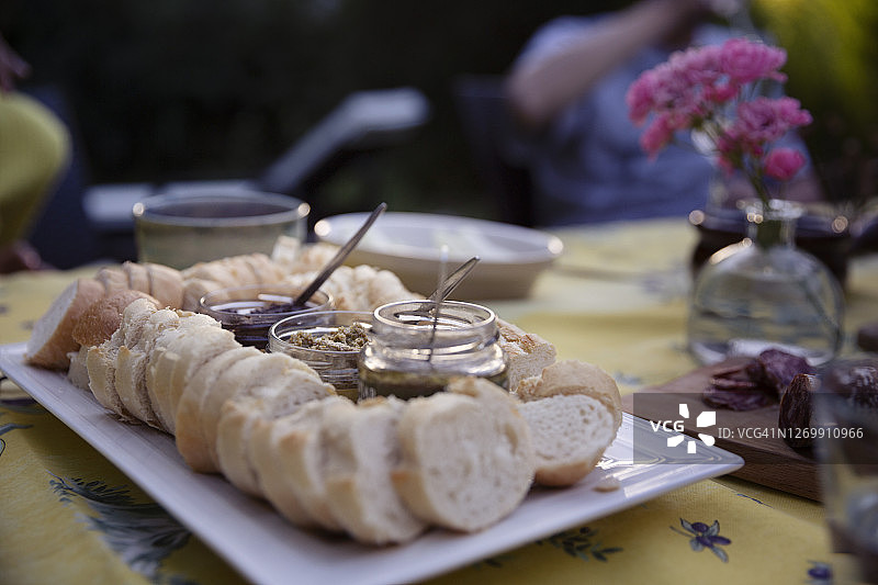 法棍切片和玻璃罐装塔佩纳酱，户外餐桌摆盘图片素材