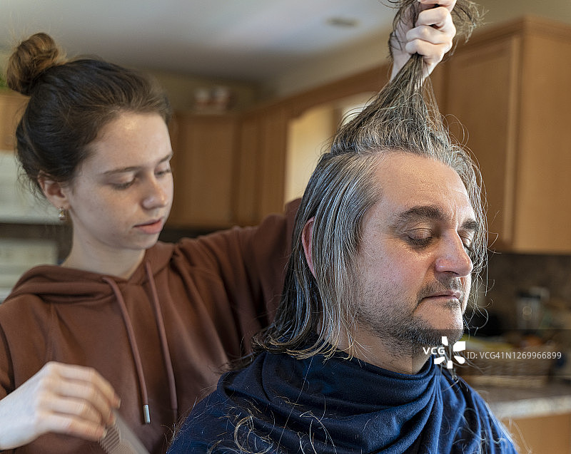 自己动手理发：一位50岁成熟男子在家理发，由女儿操刀图片素材