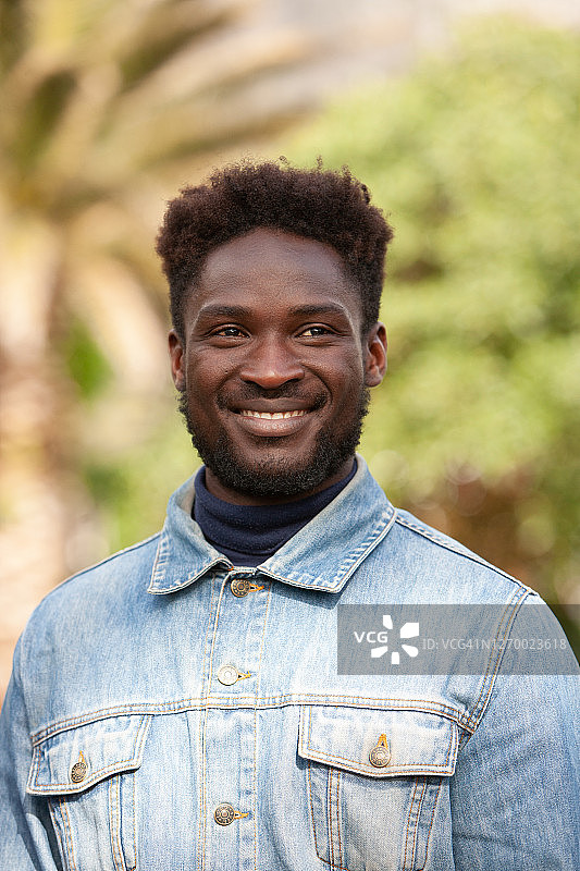 背景虚化的绿叶前英俊男子肖像图片素材