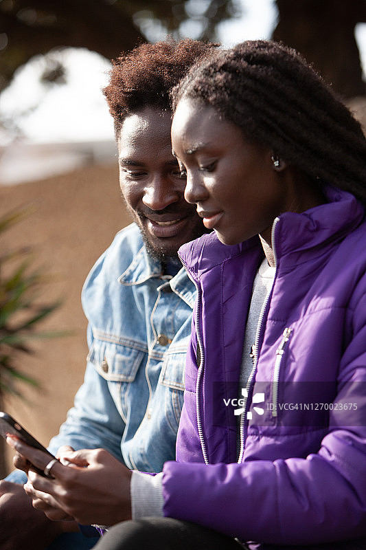 情侣坐着看手机，女人正在打字图片素材