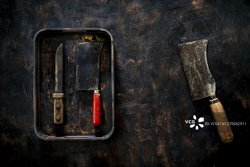 深色木质背景中的复古托盘里的肉店刀具图片素材