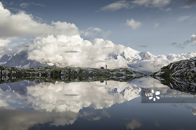 徒步旅行者眺望群山，帐篷倒映在白湖中图片素材